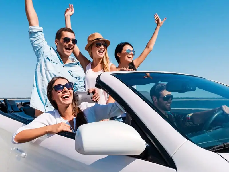 Happy friends riding a convertible car on holiday